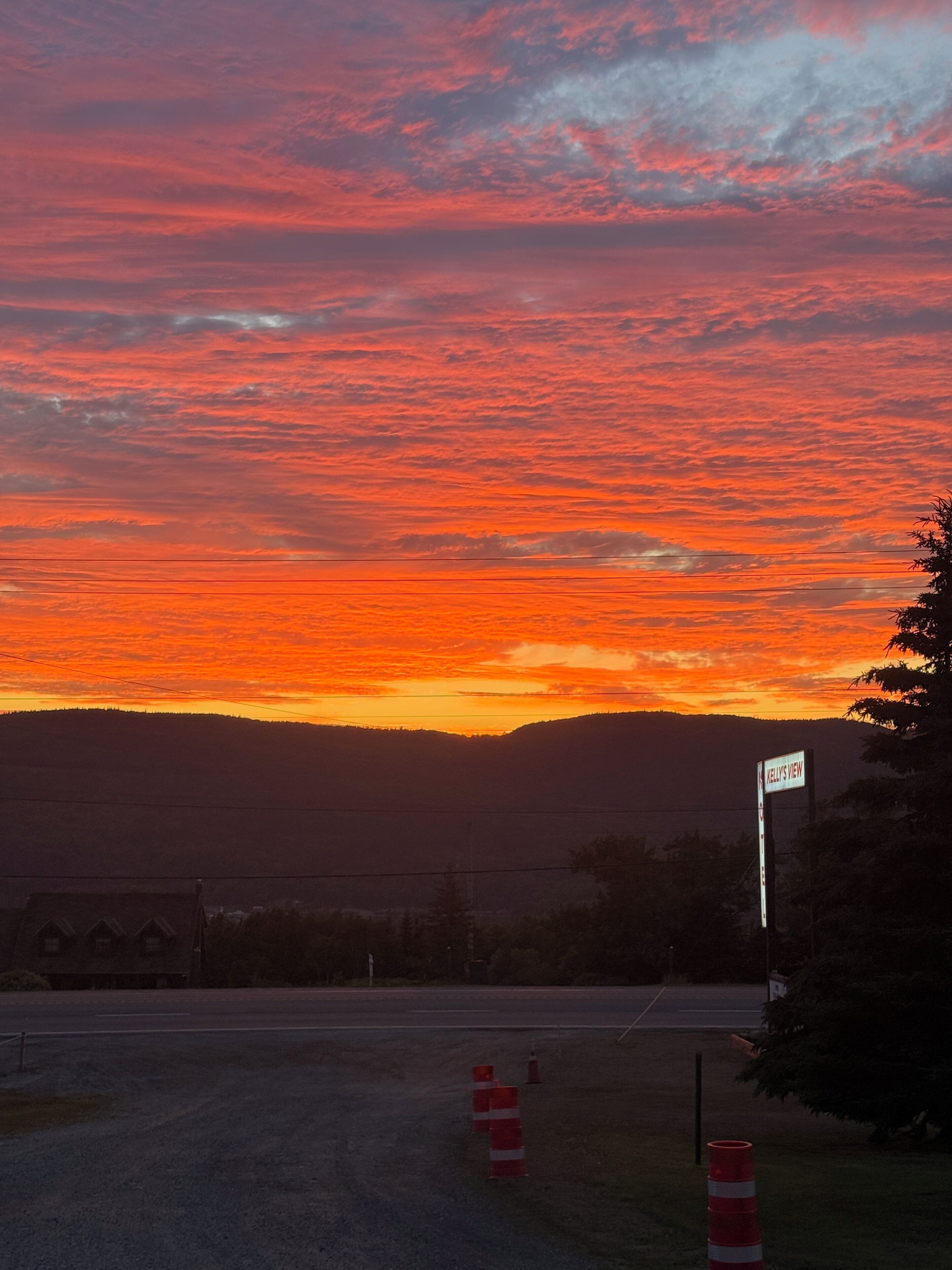 Un atardecer con cielo despejado, una carretera con conos de tráfico y un letrero que dice "Kelly's View".