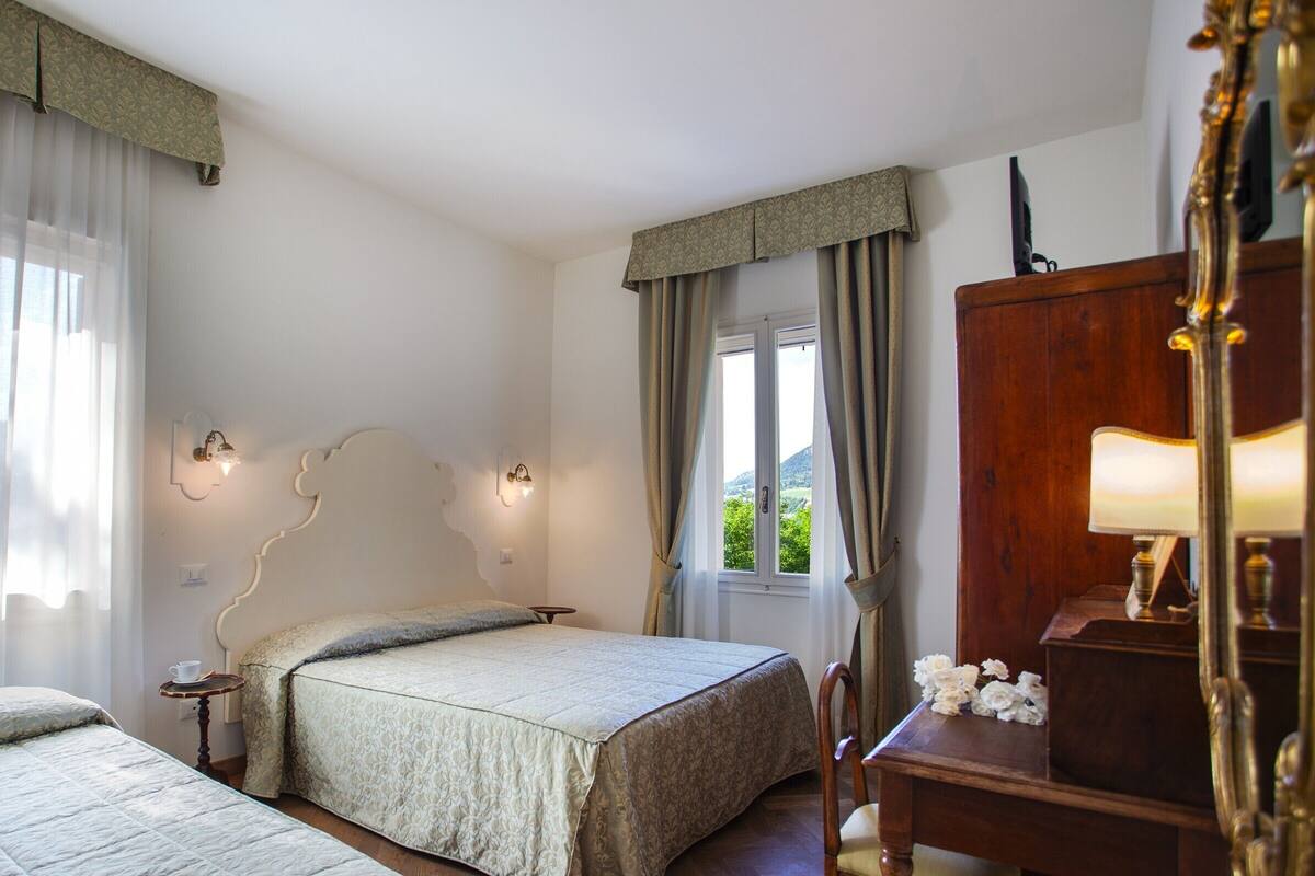 Een slaapkamer met twee bedden, een houten bureau en een spiegel.