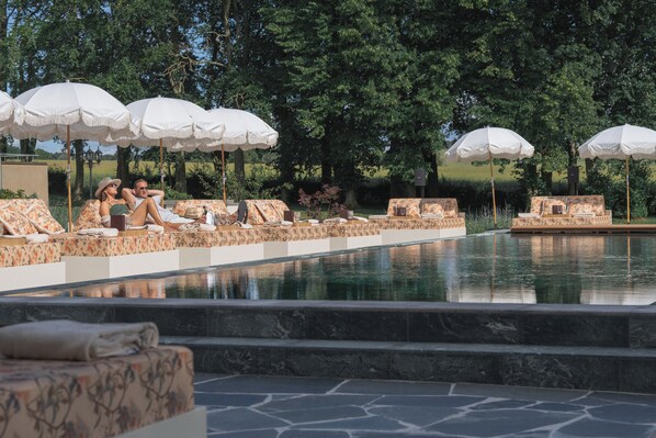 A poolside area with lounge chairs and umbrellas, surrounded by trees. - Maryhill Estate (Glumslöv)