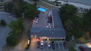 An aerial view of a hotel with a swimming pool, parking lot, and adjacent beach. - Riviera Motel (Mackinaw City)