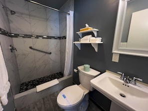 Une salle de bain équipée d’une douche, de toilettes, d’un lavabo et d’un porte-serviettes avec des serviettes.
