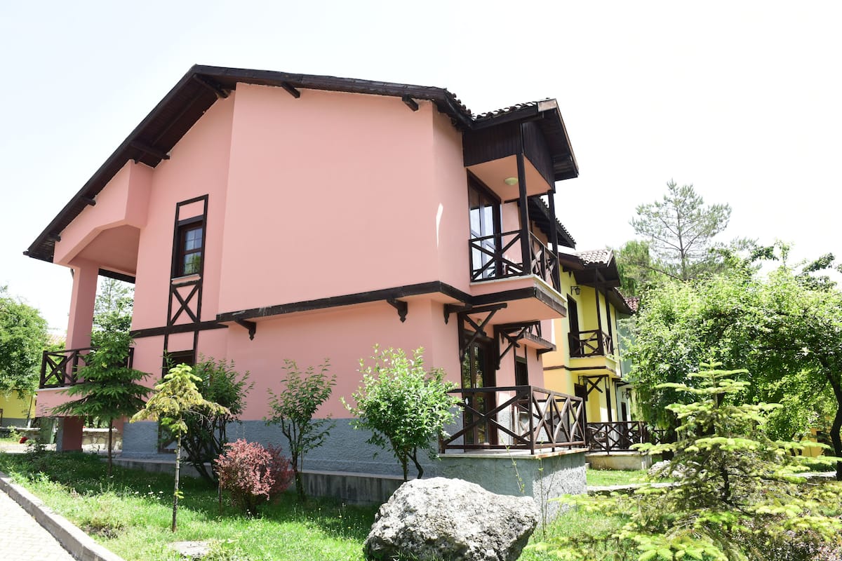 A pink and yellow building with a balcony and a stone pathway.