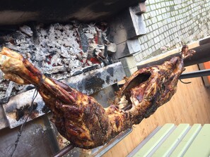 Un pollo entero asado sobre un asador, cocinándose al fuego vivo.