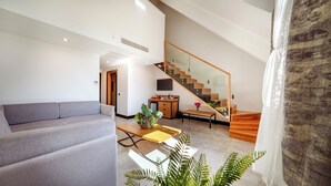 A modern living room with a grey sofa, a wooden coffee table, and a staircase leading to an upper level. - VONRESORT Abant (Bolu)