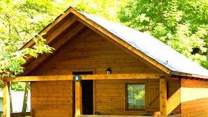 A wooden cabin with a porch, a door, and a window. - Camping Prado Verde (Vilamos)