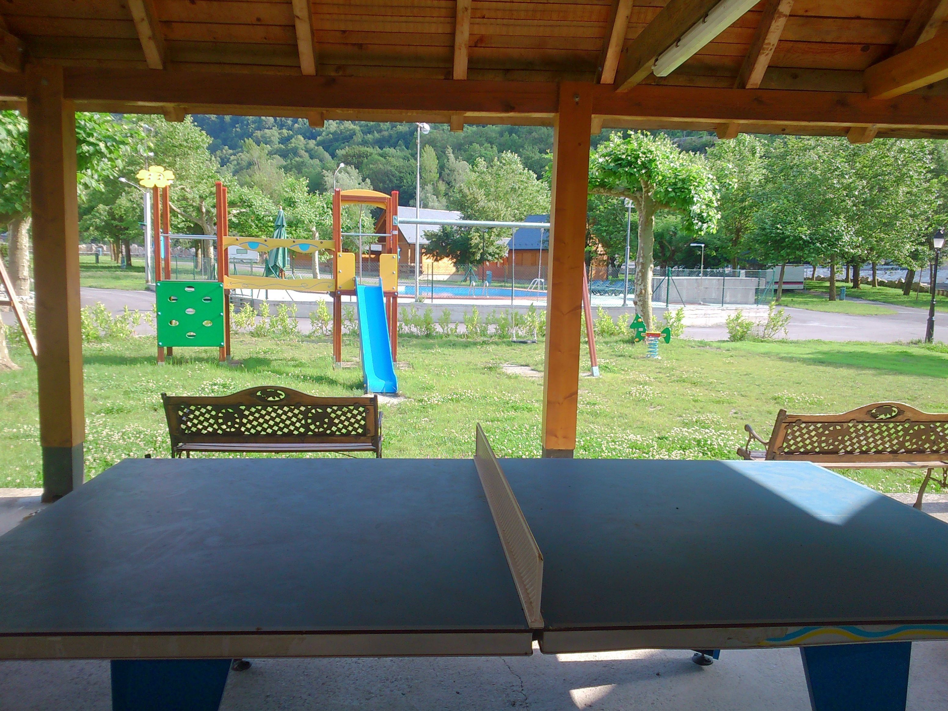 Una mesa de ping pong cubierta con bancos en un parque.