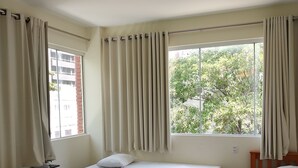 A hotel room with two single beds, a wooden chair, a small table, and a window with curtains. - Hotel Italia Meireles (Fortaleza)