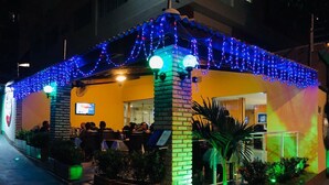 A restaurant with outdoor seating, brick pillars, and string lights. - Hotel Italia Meireles (Fortaleza)