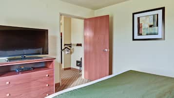 Habitación de hotel con una cama, un televisor sobre un mueble, una puerta de madera y un cuadro en la pared.