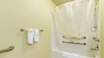 A bathroom with a bathtub, a shower curtain, and two handrails.