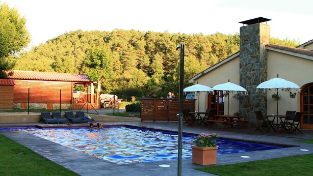 A swimming pool with a mosaic tile design, surrounded by lounge chairs and umbrellas.