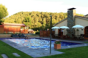 A swimming pool with a mosaic tile design, surrounded by lounge chairs and umbrellas. - Camping Puigcercós (Borreda)