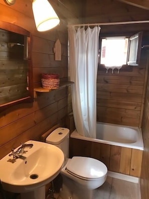A wooden cabin bathroom with a sink, toilet, and bathtub.