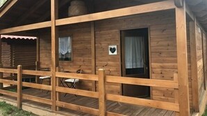 A wooden cabin with a porch, a small table, and a chair.