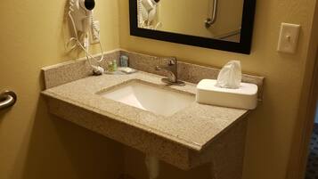 A bathroom with a granite countertop sink, a mirror, a hairdryer, and a towel on the counter.
