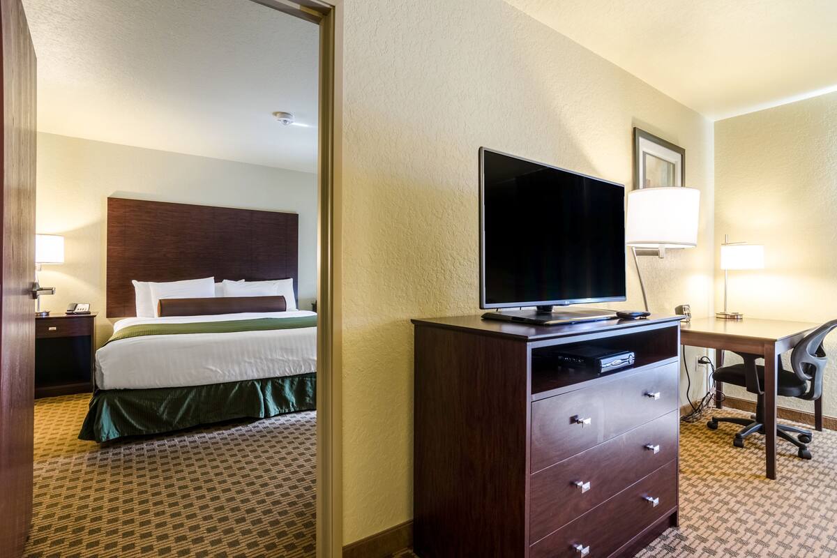 Une chambre d’hôtel avec un lit, un téléviseur posé sur une commode, un bureau et une chaise.