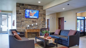 Eine Lobby mit Steinwand, einem Fernseher, einer Sitzecke mit Sofa und Sesseln, einem Couchtisch mit Pflanze und einem Pepsi-Kühlschrank.