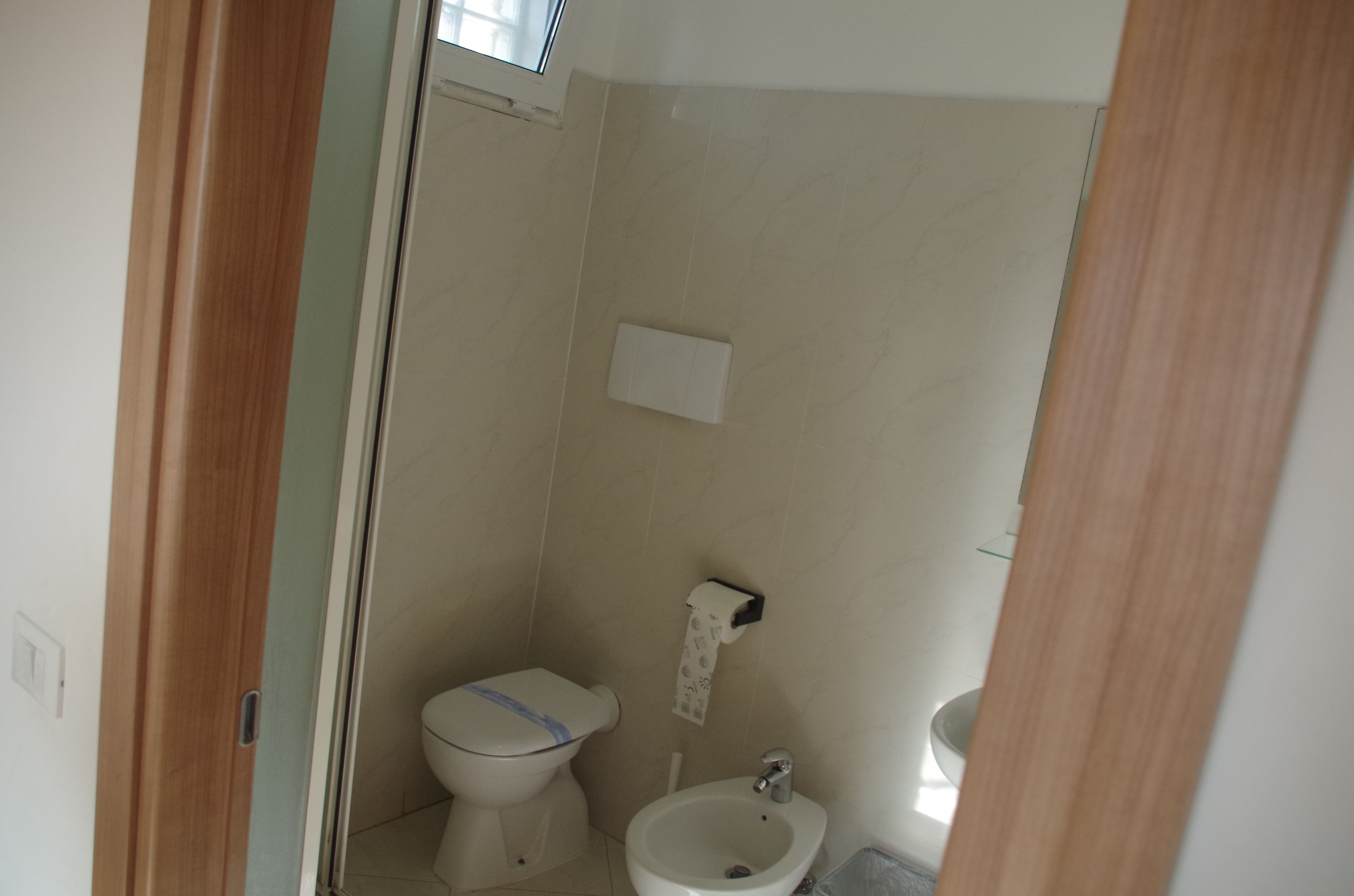 Un bagno piccolo e pulito con un water, un bidet e un dispenser di carta.
