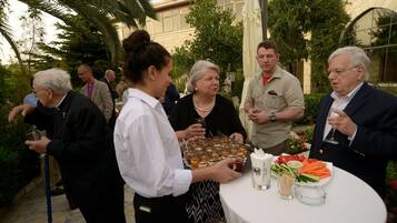 A group of people at an outdoor event with a table set with food and drinks.