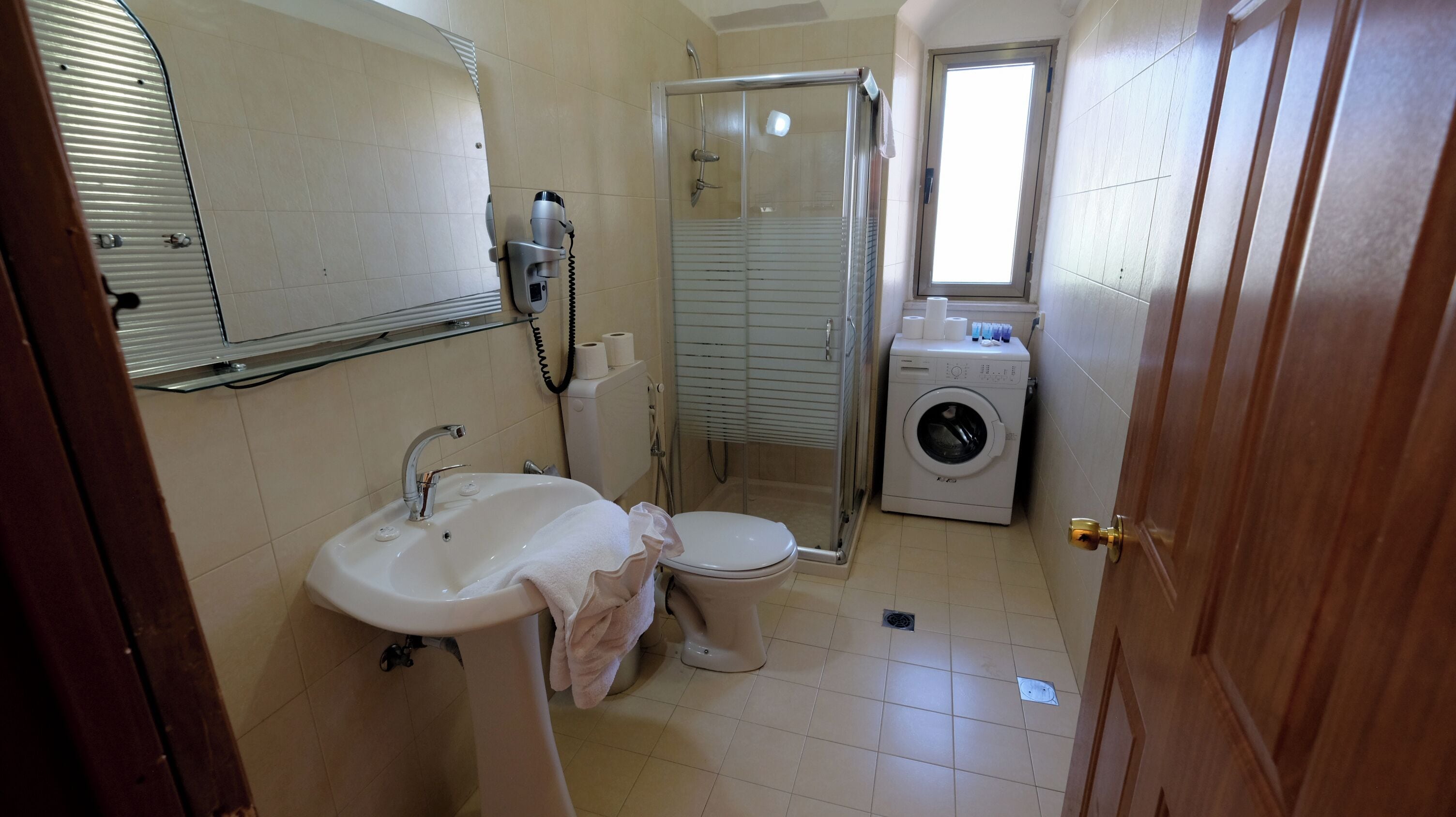 A compact bathroom with a sink, toilet, and a glass-enclosed shower.