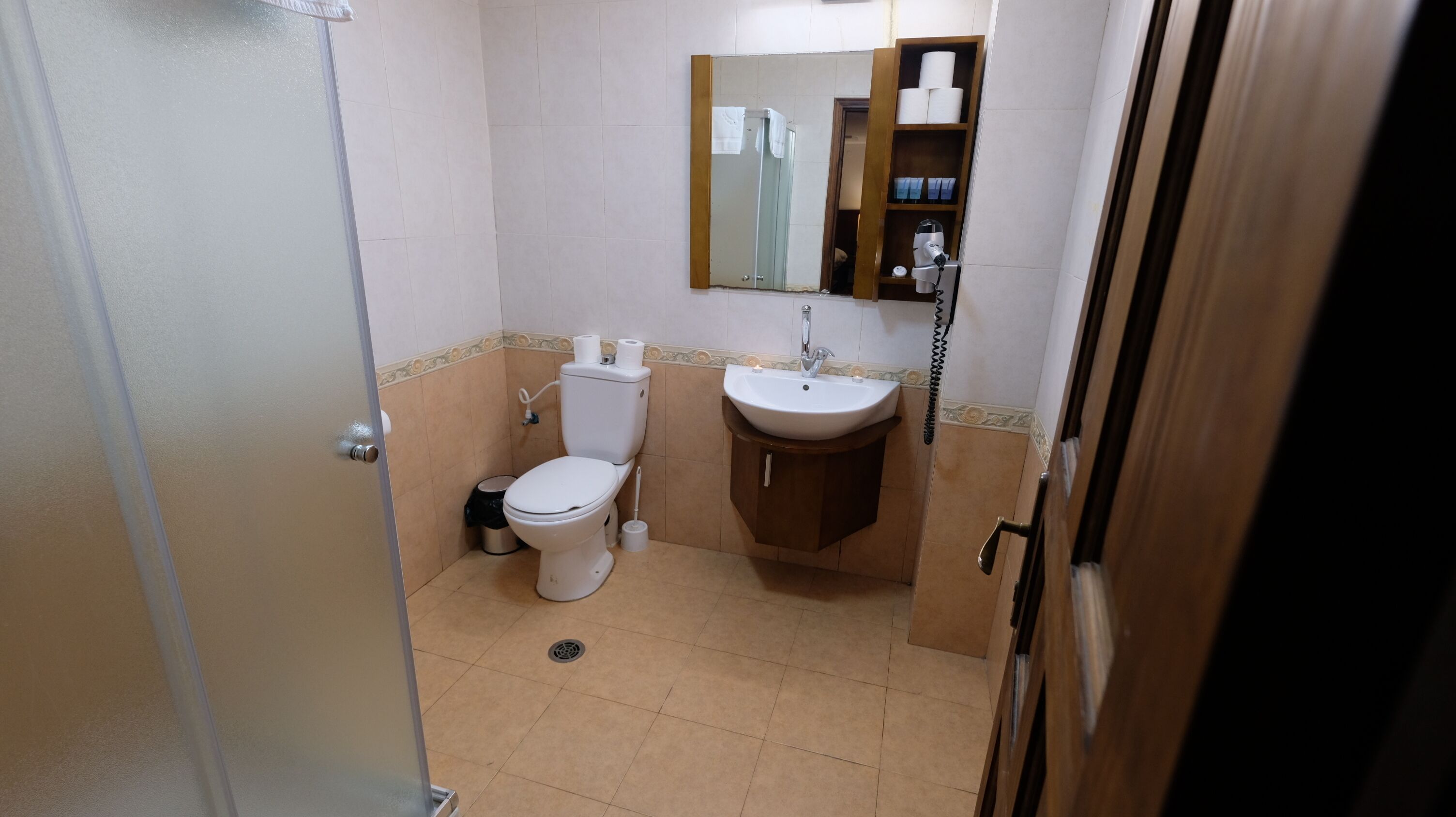 A small bathroom with a toilet, sink, and mirror.