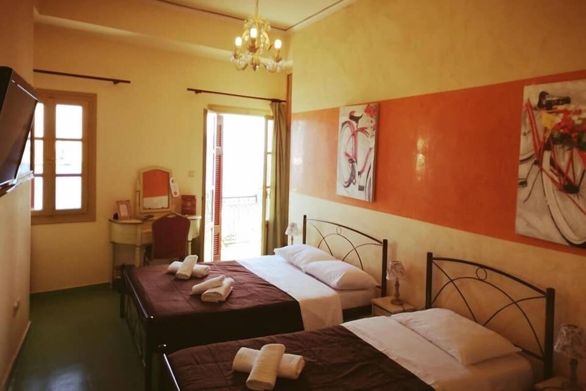 A hotel room with two beds, a desk with a chair, a desk lamp, a telephone, and a painting on the wall.