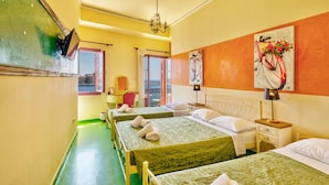 A hotel room with three beds, a balcony with a view, and a painting of a bicycle. - Florence (Syros)