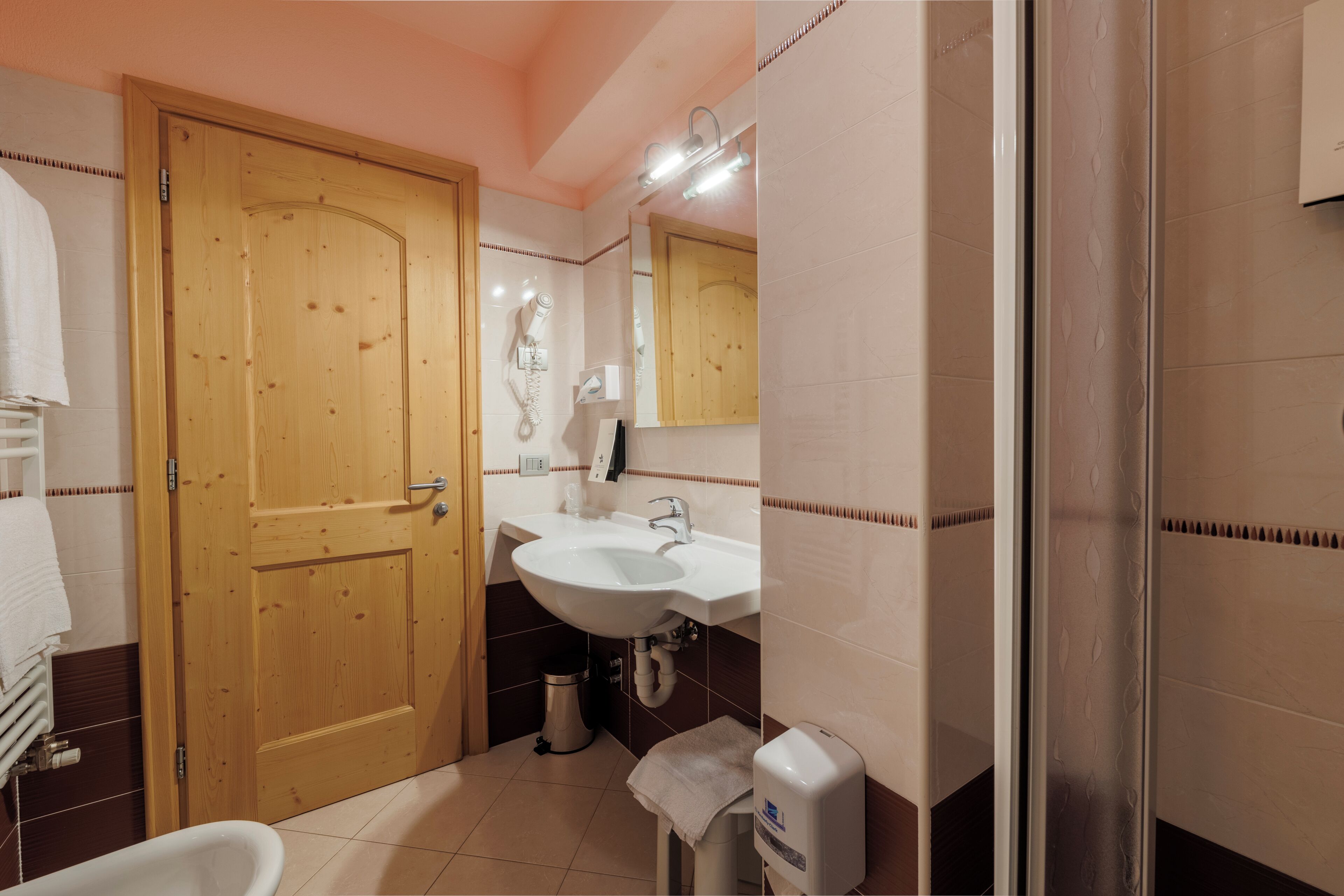 Une salle de bain avec une porte en bois, un lavabo, un miroir et un porte-serviettes.