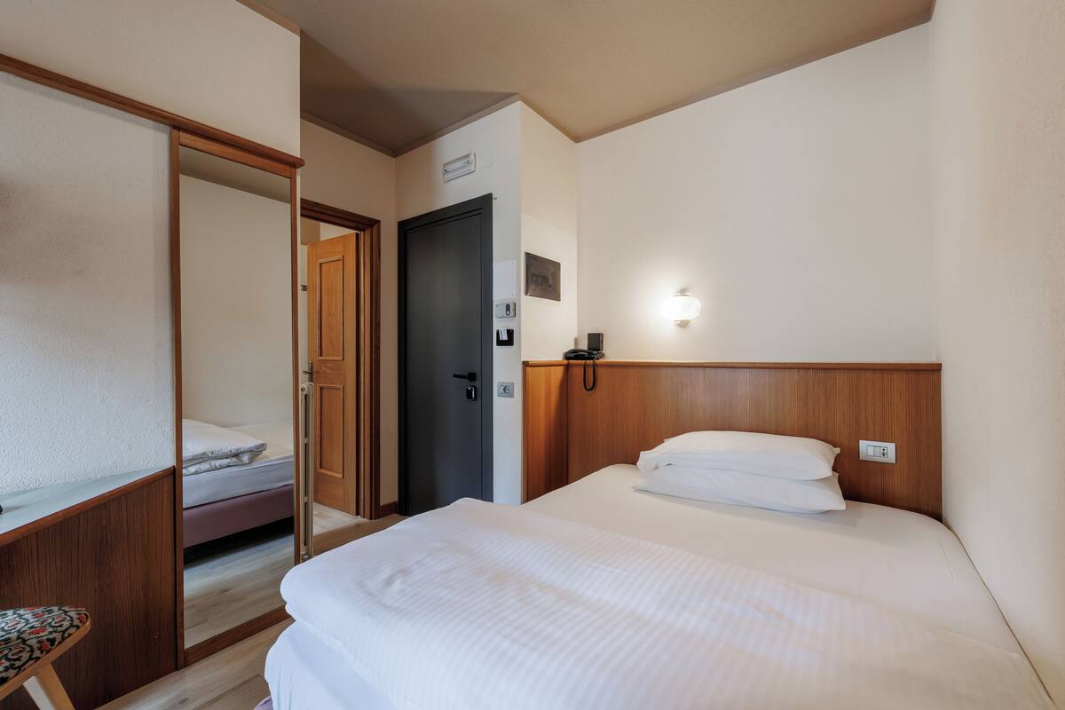 Una habitación de hotel con cama, escritorio, armario y puerta.