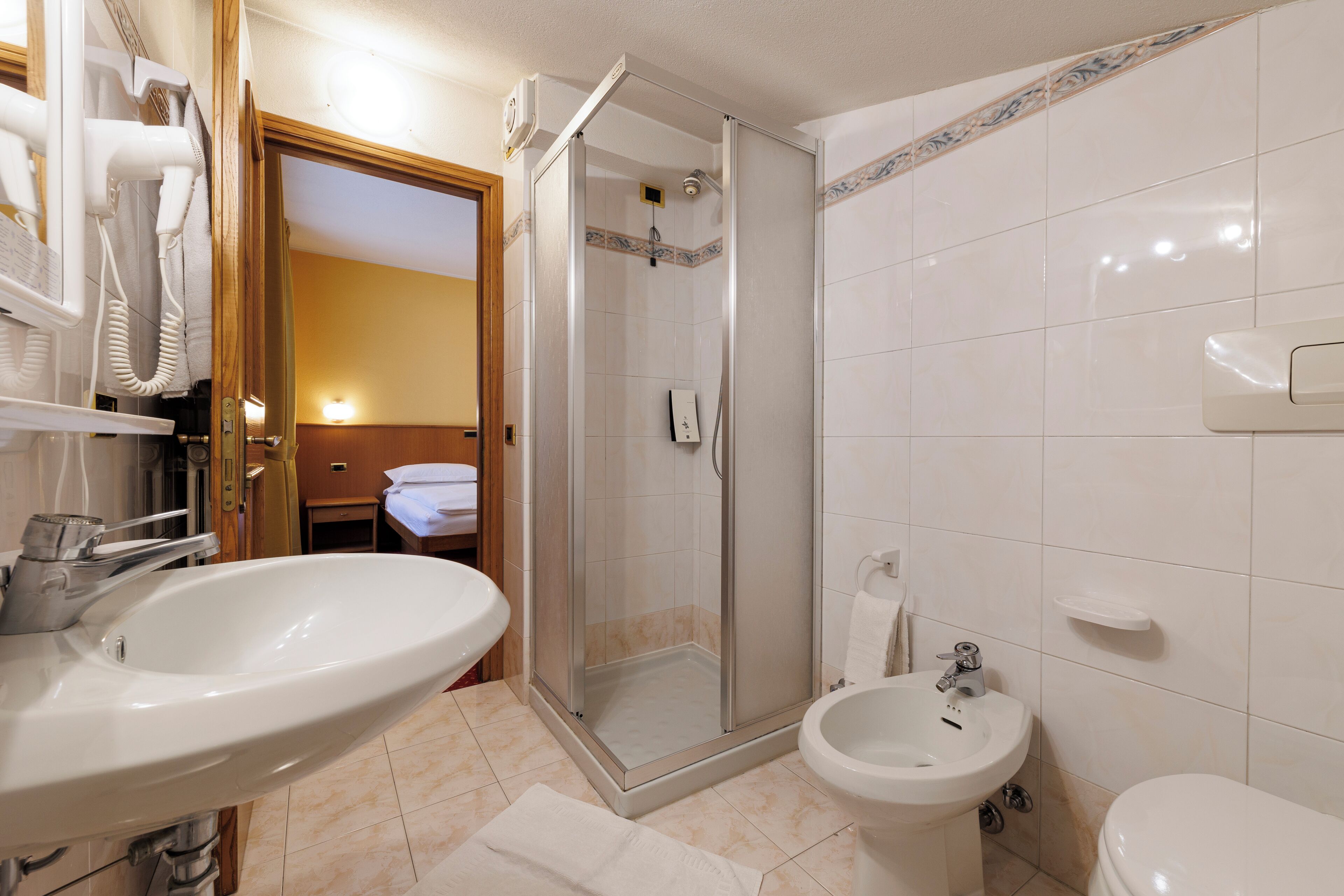 A bathroom with a sink, bidet, toilet, and a glass-enclosed shower.