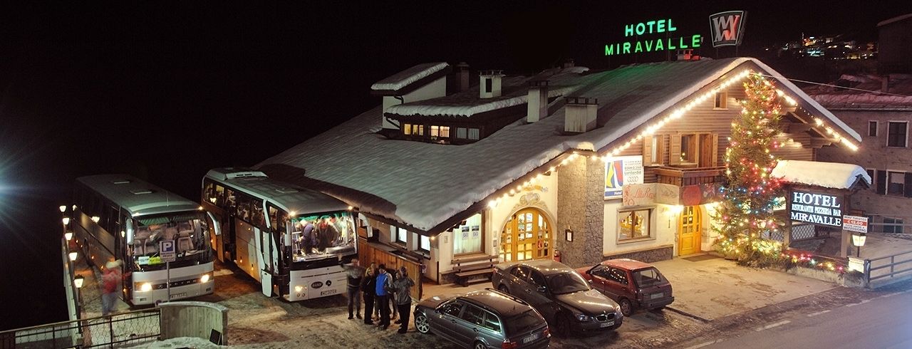 Un hotel con techo nevado, un árbol de Navidad y varios coches aparcados.