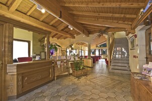 A lobby with a wooden reception desk, a staircase, and a tiled floor.