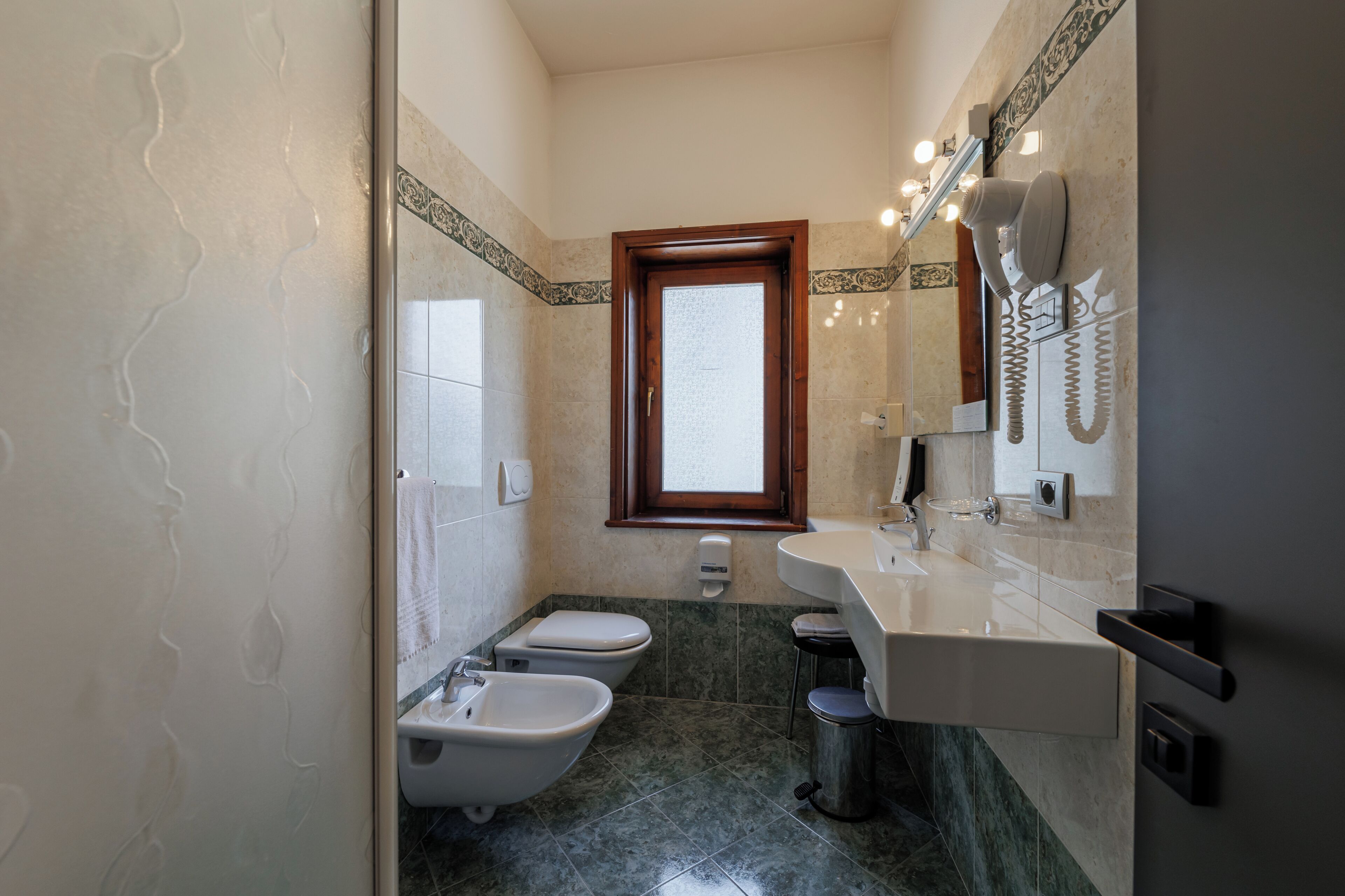 A bathroom with a toilet, bidet, sink, and mirror.