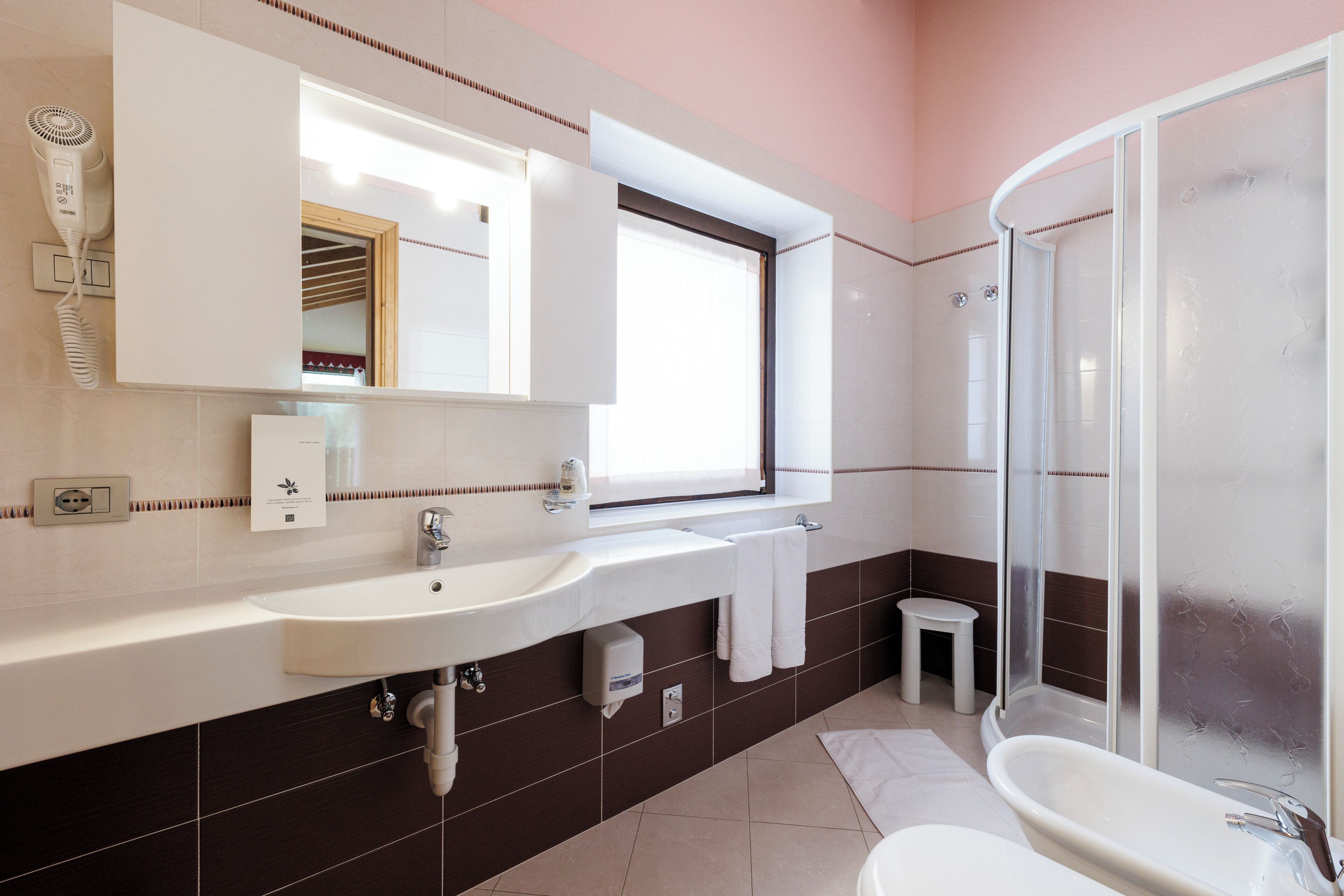 A bathroom with a sink, mirror, towel rack, and shower.