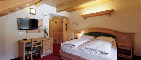 A bedroom with a bed, wooden desk, television, and wardrobe.
