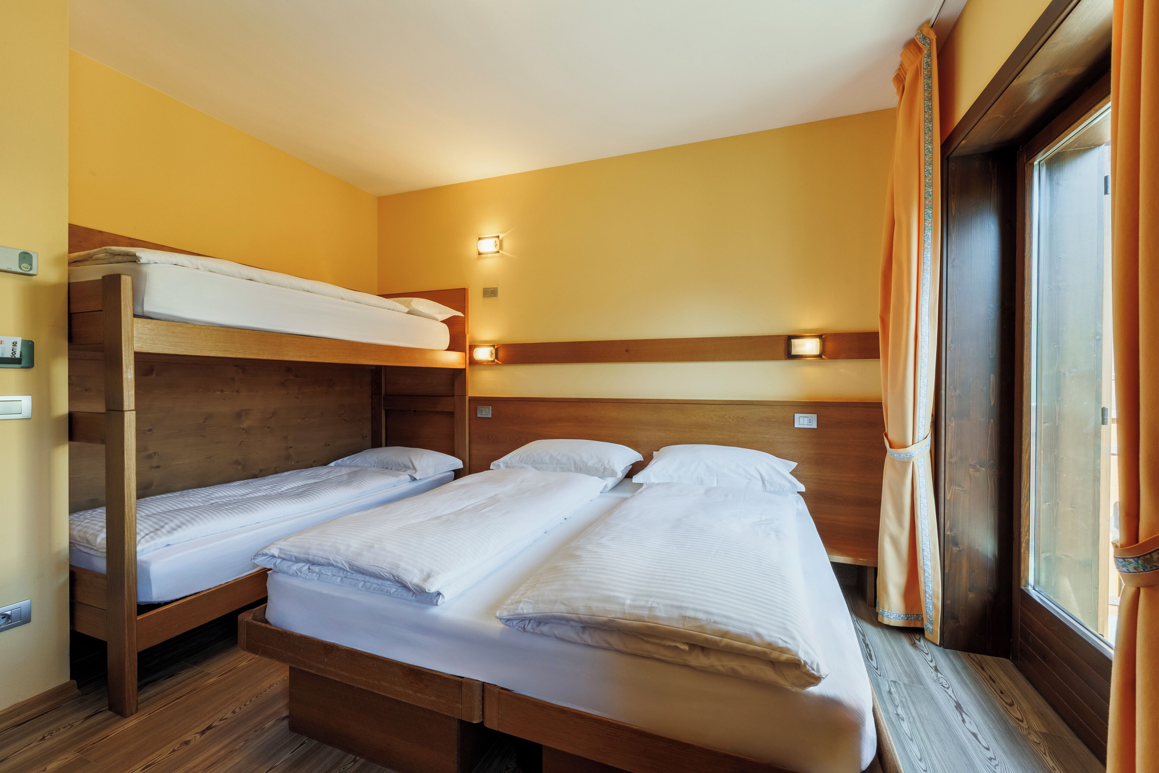 Een kamer met twee stapelbedden, houten hoofdeinden en bedlampjes.