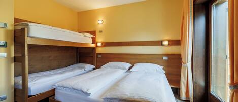 Een kamer met twee stapelbedden, houten hoofdeinden en bedlampjes.