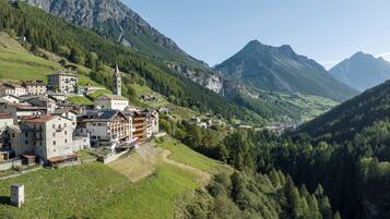 A mountainous village with traditional buildings, a church, and a river.
