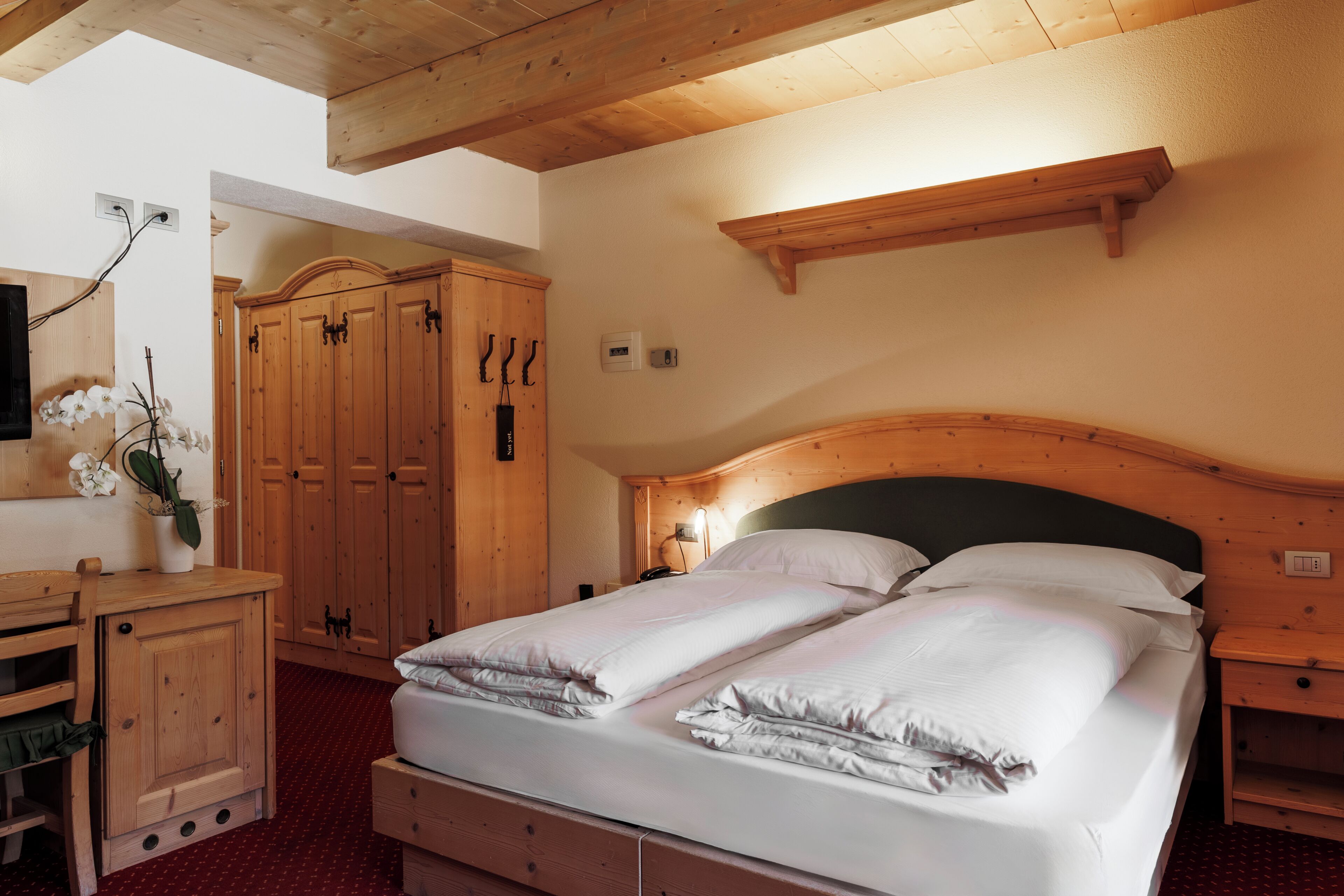 Una camera da letto con una testiera in legno, un letto con lenzuola bianche, un comò in legno e un armadio.