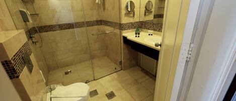 Un baño moderno con ducha acristalada, inodoro blanco y lavabo con espejo.