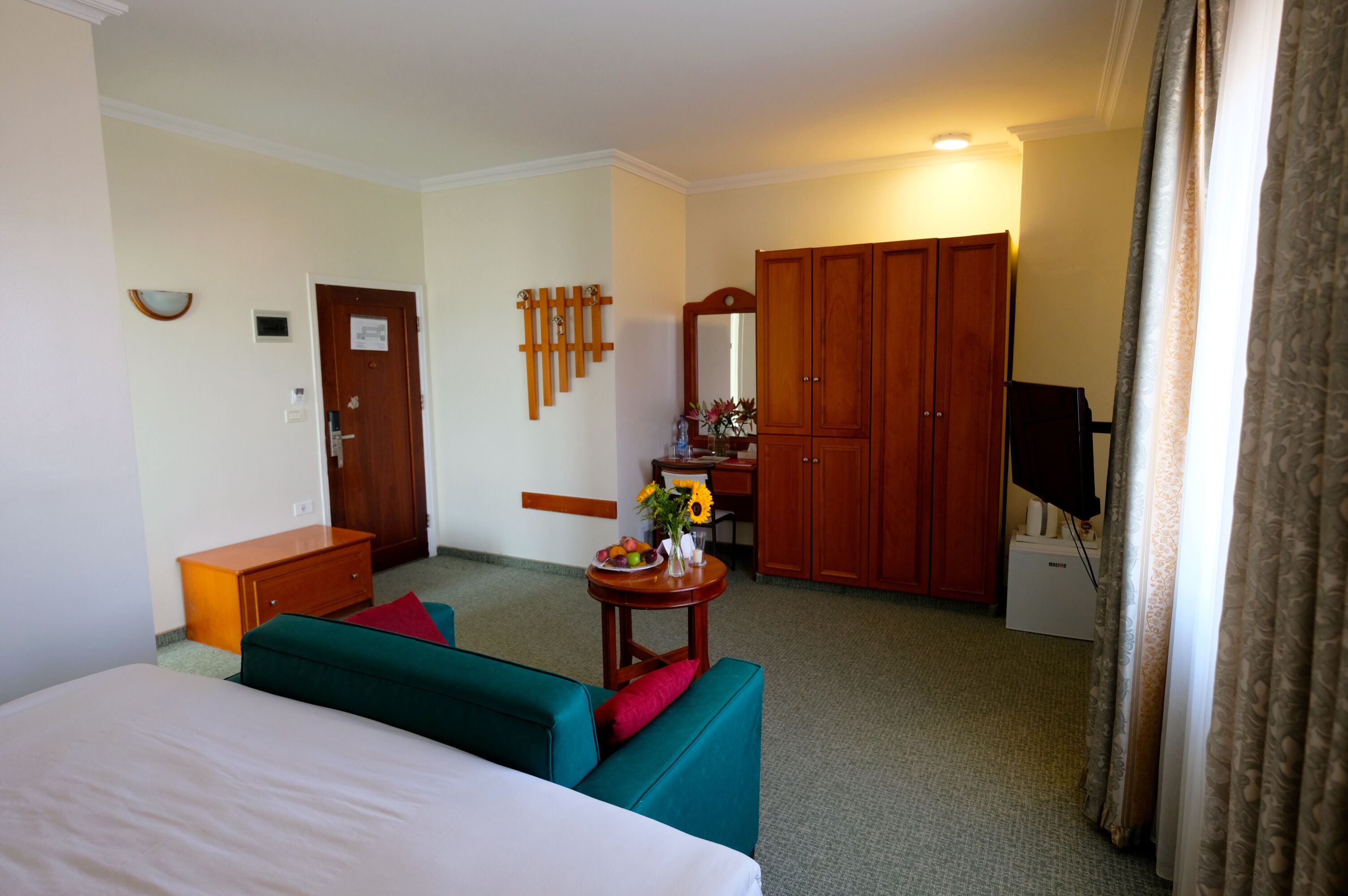 A hotel room with a bed, a desk, a television, and a wardrobe.