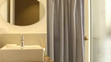 Un baño con un lavabo rectangular, un espejo y una cortina de ducha.