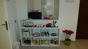 A kitchen area with a microwave, kettle, and various kitchen utensils on a shelf. - Palermo Rooms (Palermo)