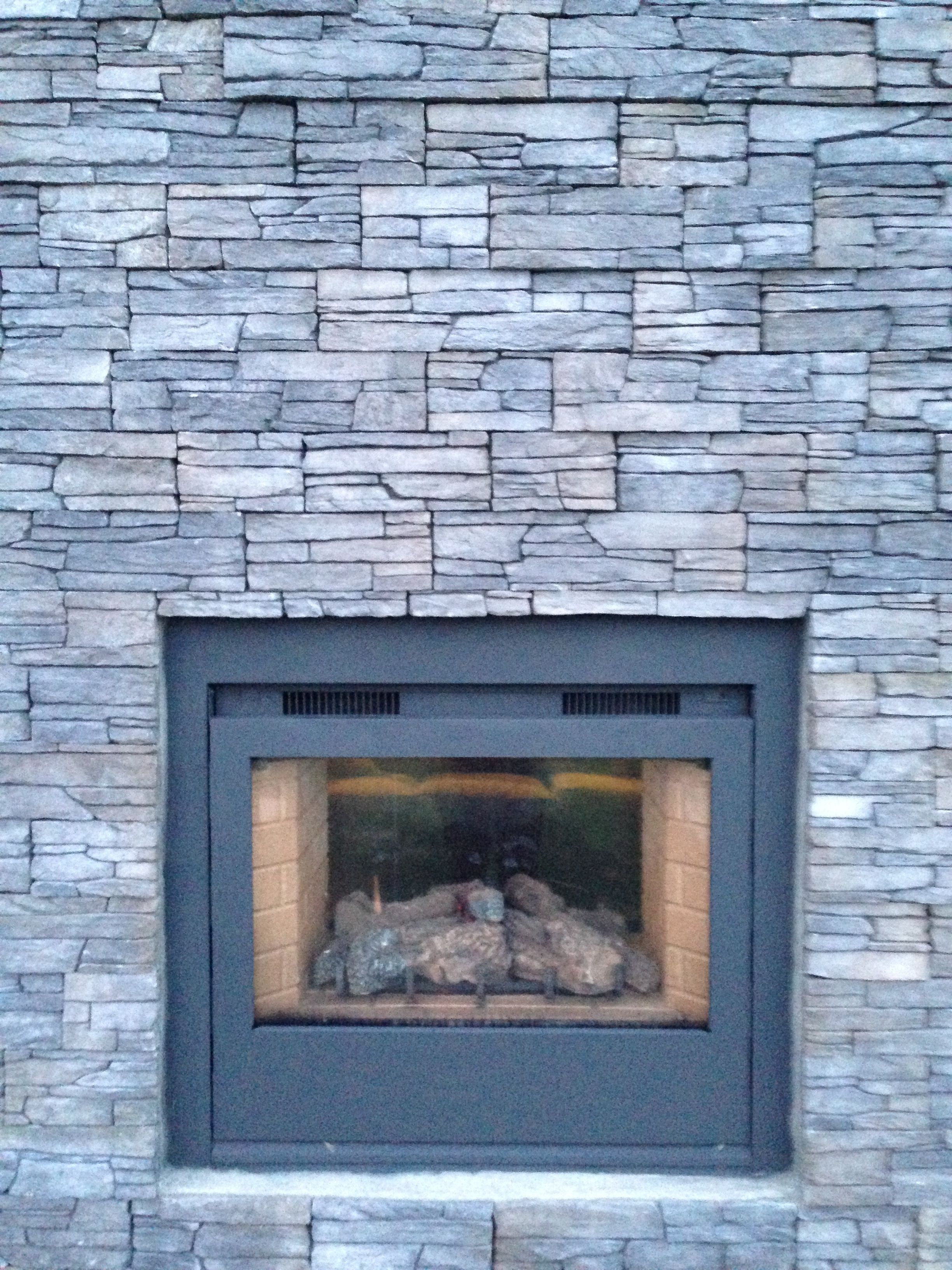 A stone wall with a rectangular fireplace.