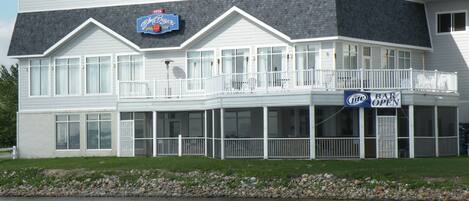 A waterfront building with a bar open sign, a sports team logo, and a beer brand logo.