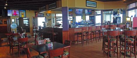 A restaurant with wooden tables and chairs, a bar area, and a counter with a coffee machine.