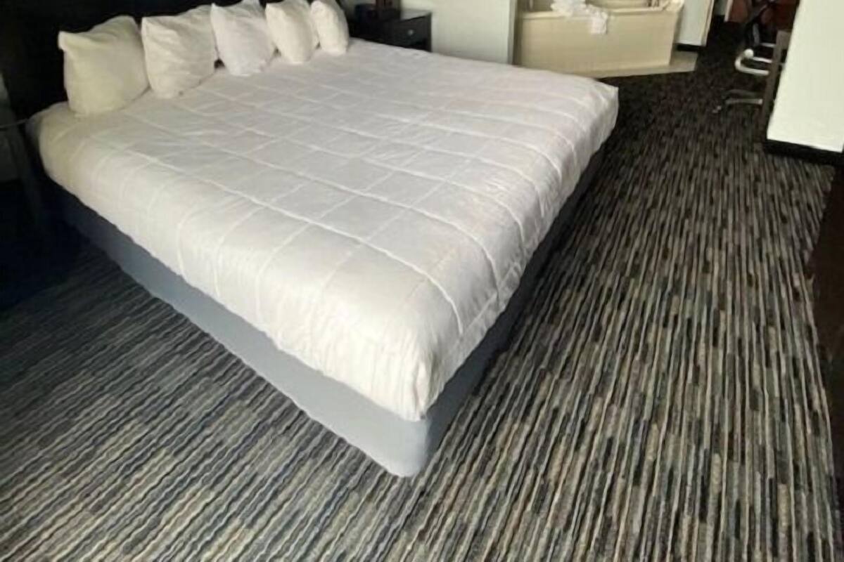 A hotel room with a large bed, a desk, a chair, and a bathroom.
