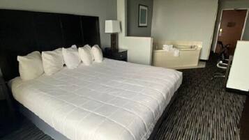 A hotel room with a large bed, a desk, a chair, and a bathroom.