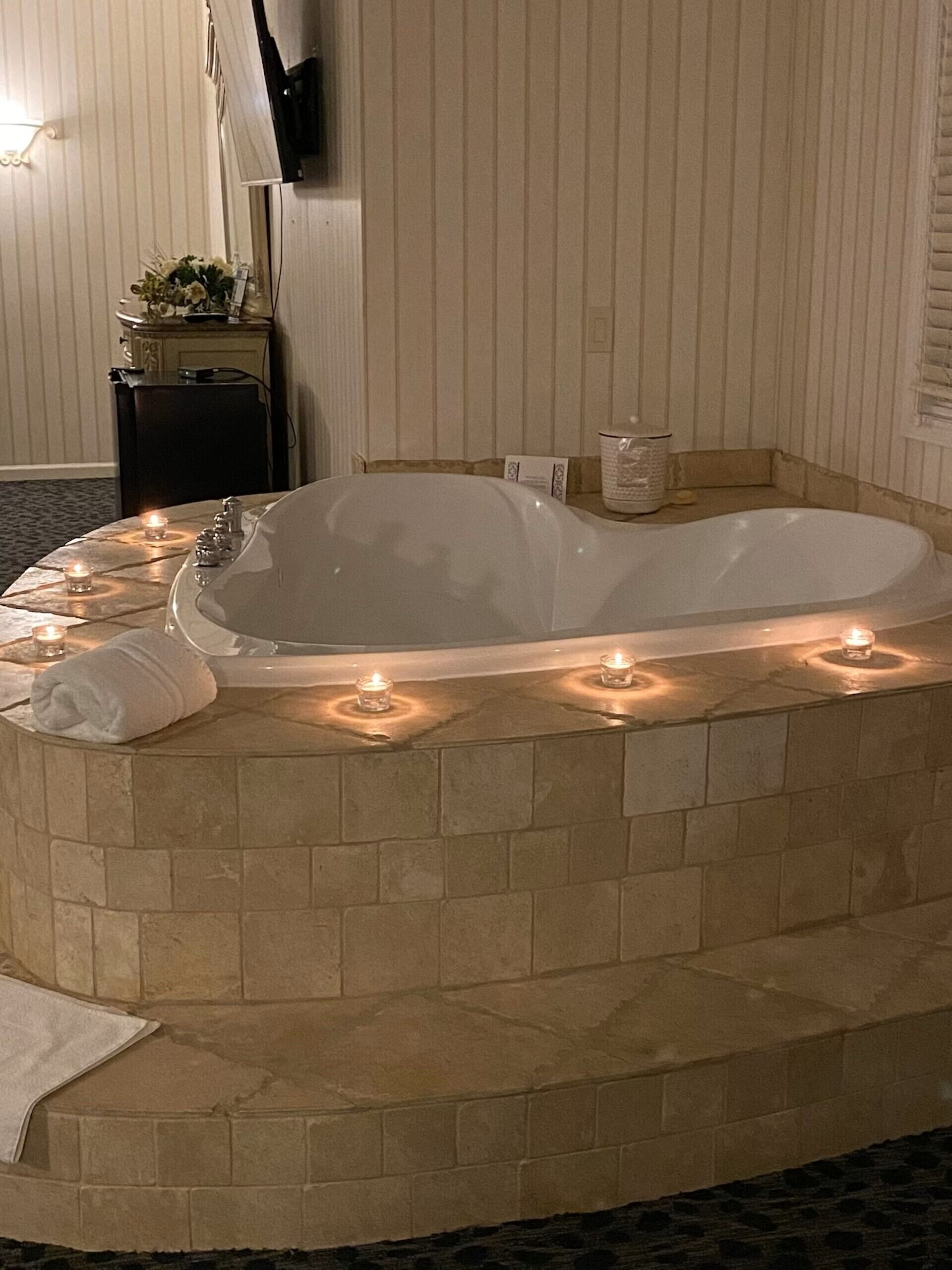 A spa-like bathroom with a freestanding bathtub, candles, and a towel.