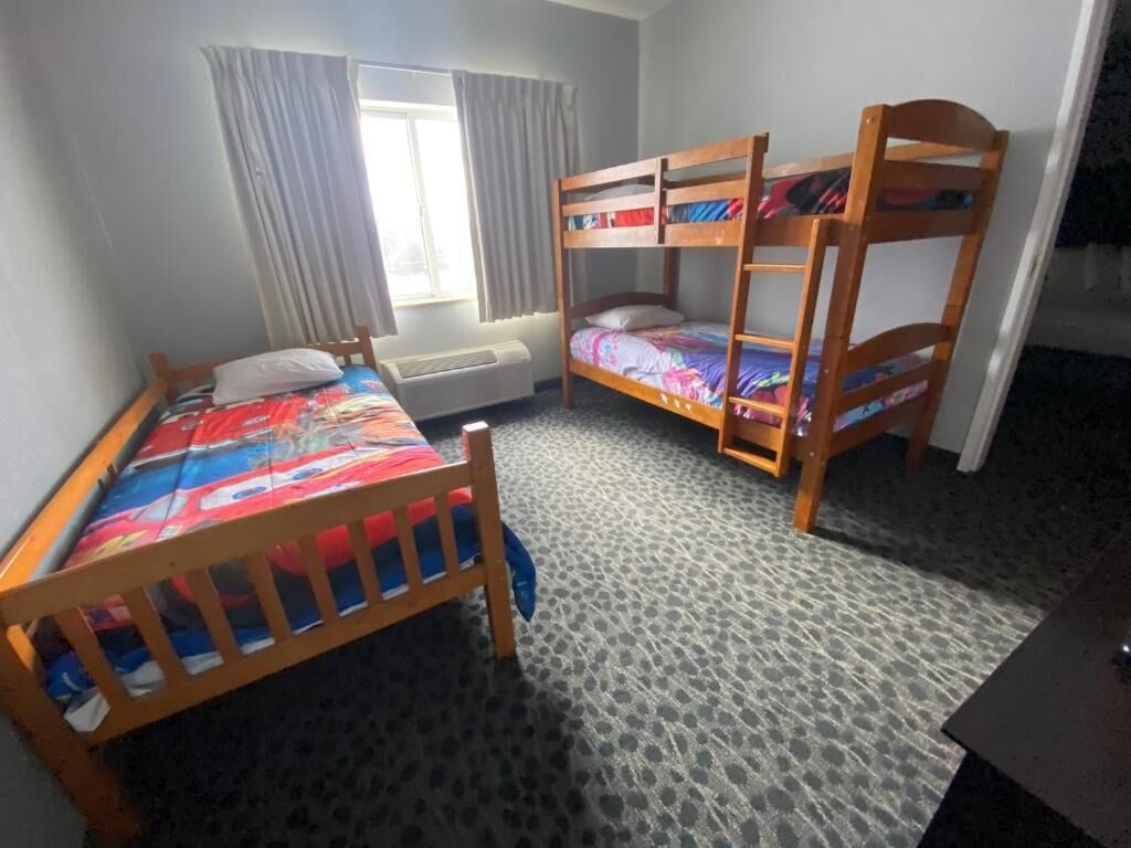 A room with bunk beds, a window with curtains, and a radiator.